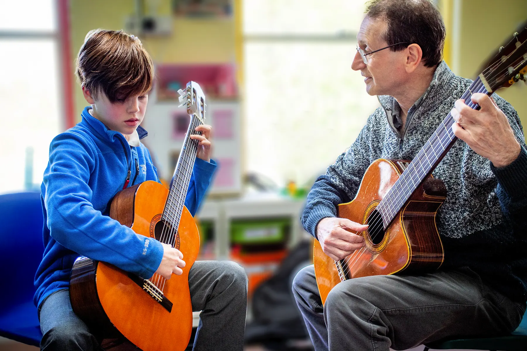 Boy with music teacher having guitar lessons
